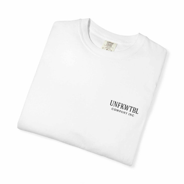 Folded white unisex T-shirt with small UNFKWTBL Company Inc logo on front, made of 100% US cotton, featuring Chucky cocktail design for horror fans.