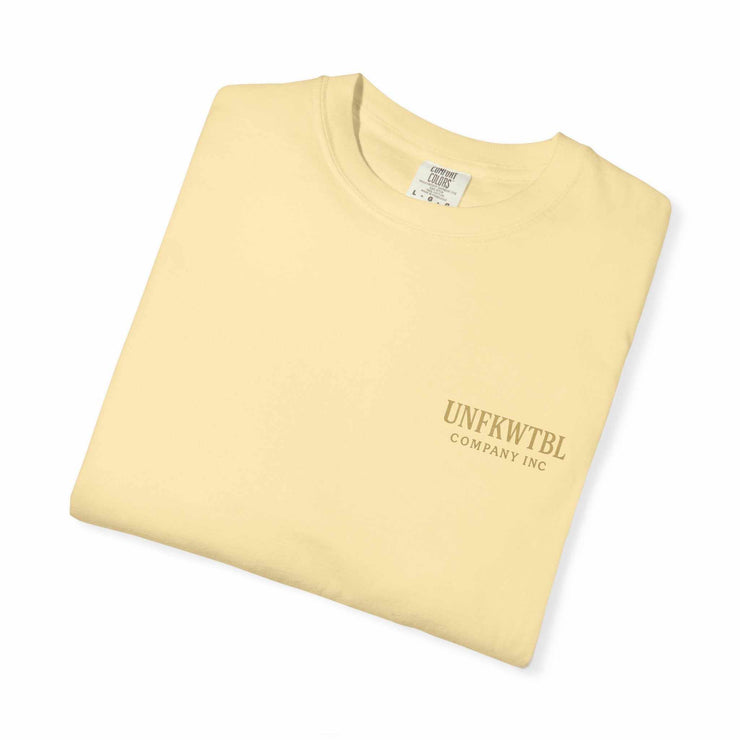 Folded beige Medusa Beauty unisex T-shirt with UNFKWTBL Company Inc logo.