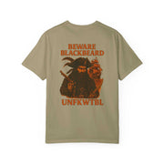Blackbeard the Pirate graphic on khaki garment-dyed T-shirt with bold warning text and pirate ship background