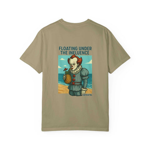 Unisex beige graphic t-shirt featuring Pennywise holding a pineapple with text "FLOATING UNDER THE INFLUENCE" on beach background
