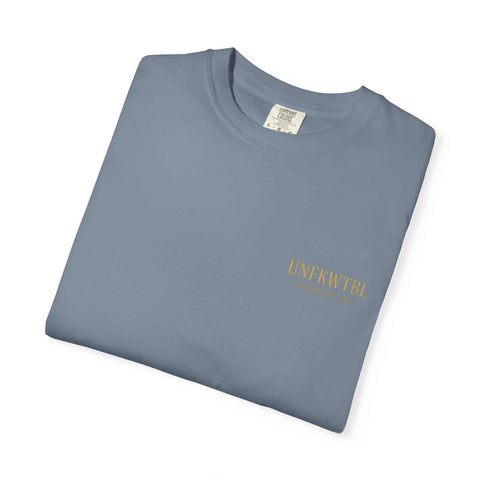 Folded blue Medusa Beauty Unisex T-shirt with small gold UNFKWTBL Company logo on front, made of 100% cotton.